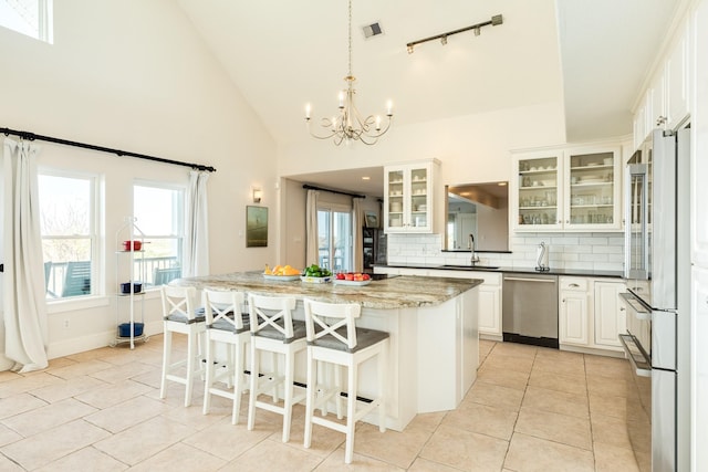 kitchen featuring appliances with stainless steel finishes, sink, white cabinets, dark stone counters, and a center island