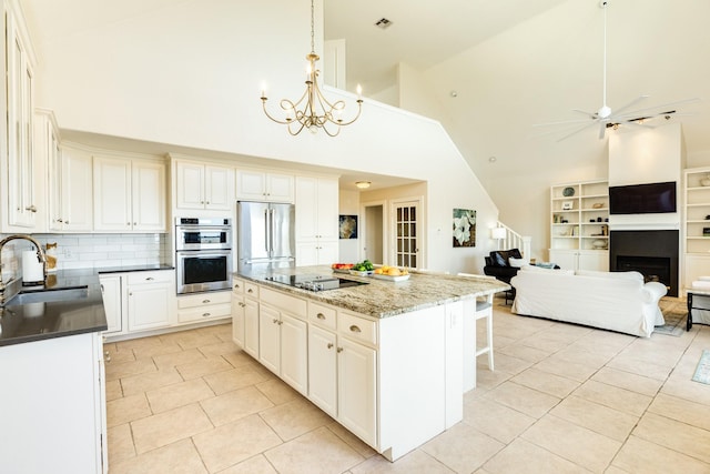 kitchen with pendant lighting, sink, dark stone countertops, stainless steel appliances, and a kitchen island