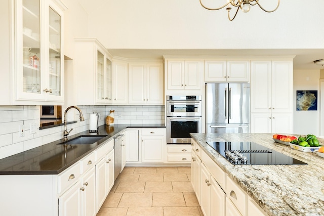 kitchen featuring sink, white cabinets, decorative backsplash, dark stone counters, and stainless steel appliances