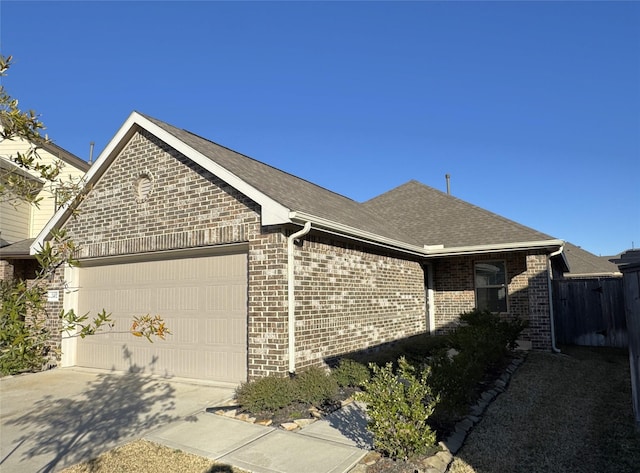 view of front of house featuring an attached garage, driveway, a shingled roof, and brick siding