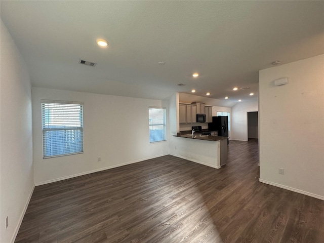 unfurnished living room featuring a wealth of natural light, dark hardwood / wood-style floors, and vaulted ceiling