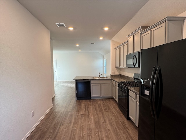 kitchen with visible vents, dark wood-type flooring, a sink, a peninsula, and black appliances