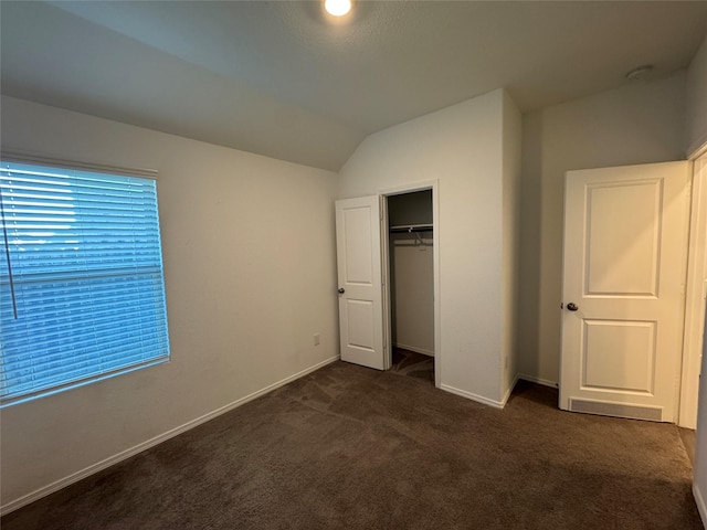 unfurnished bedroom with vaulted ceiling, baseboards, dark colored carpet, and a closet