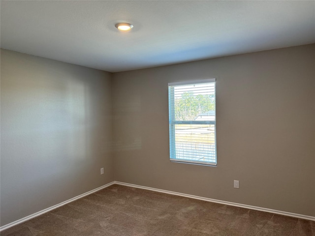 spare room with dark carpet and baseboards