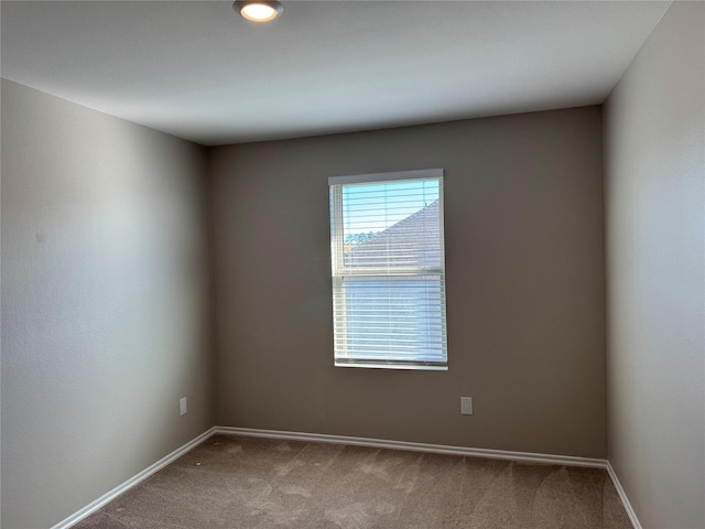 carpeted spare room featuring baseboards