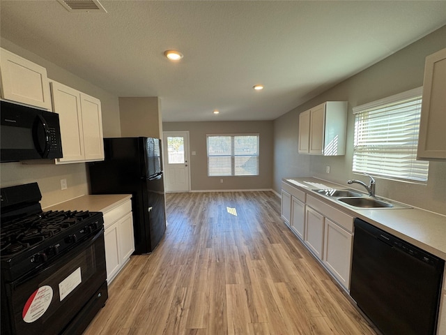 kitchen featuring black appliances, a sink, light countertops, and light wood-style floors