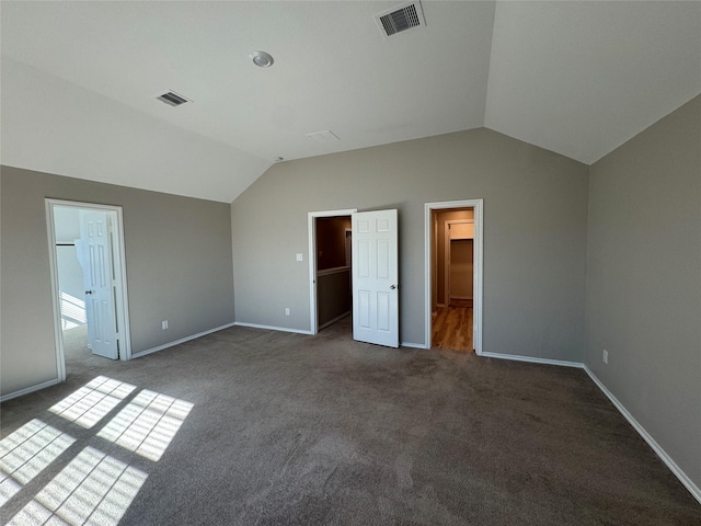 unfurnished bedroom with lofted ceiling, a walk in closet, and visible vents