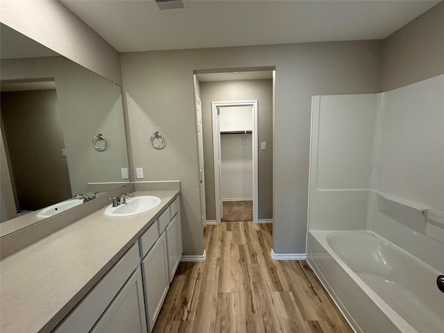 full bath featuring visible vents, baseboards, wood finished floors, a spacious closet, and vanity