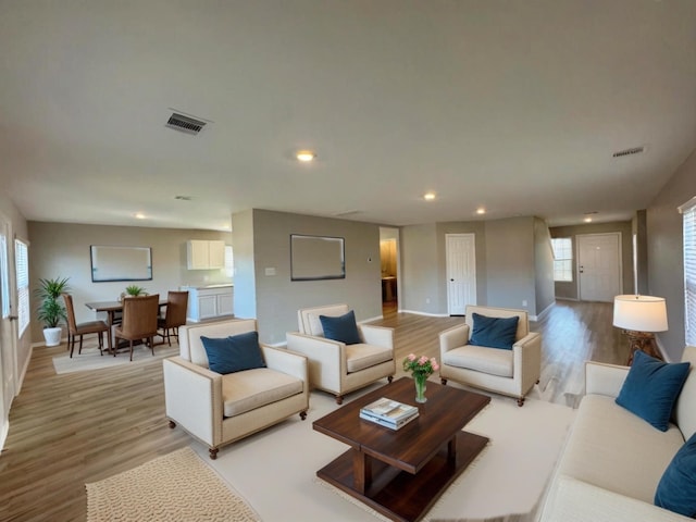 living room with light wood finished floors, plenty of natural light, visible vents, and recessed lighting