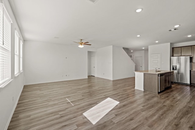 kitchen featuring sink, ceiling fan, appliances with stainless steel finishes, wood-type flooring, and a center island with sink