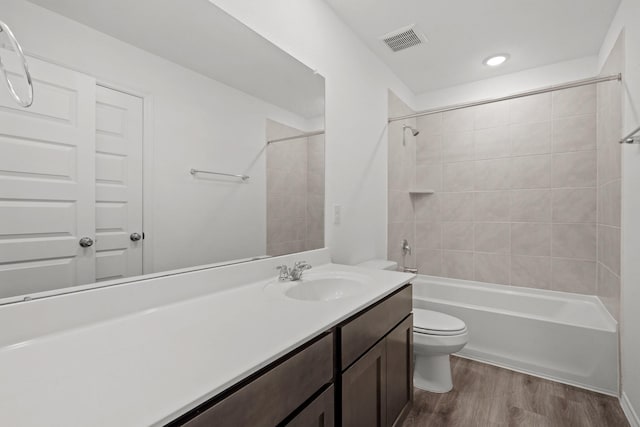 full bathroom featuring wood-type flooring, toilet, tiled shower / bath combo, and vanity