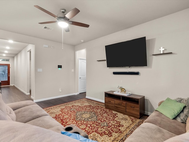 living room featuring dark wood-type flooring and ceiling fan