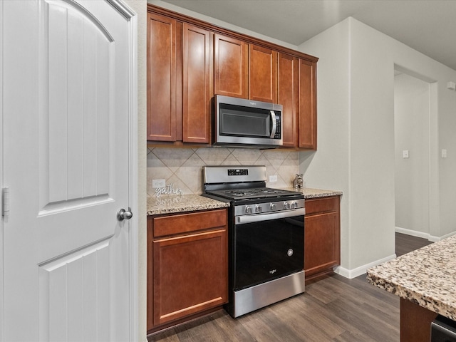 kitchen with light stone countertops, backsplash, dark wood-type flooring, and stainless steel appliances