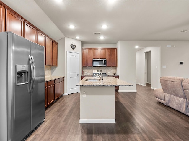 kitchen featuring sink, appliances with stainless steel finishes, a kitchen island with sink, dark hardwood / wood-style floors, and light stone countertops