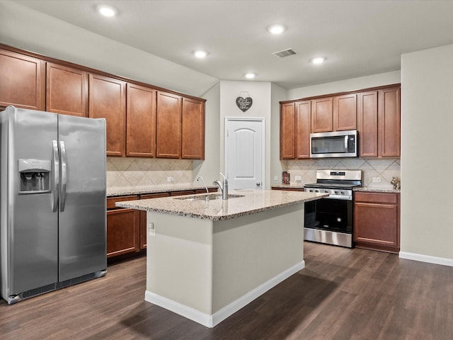 kitchen with sink, light stone counters, a center island with sink, appliances with stainless steel finishes, and dark hardwood / wood-style floors