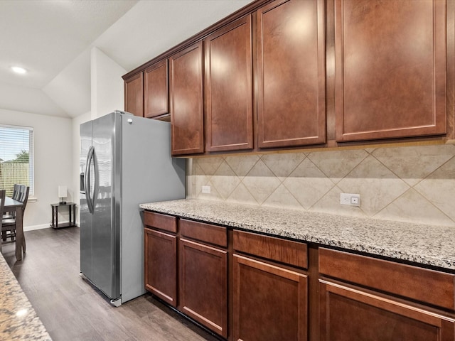 kitchen with light stone counters, stainless steel fridge with ice dispenser, decorative backsplash, and light wood-type flooring