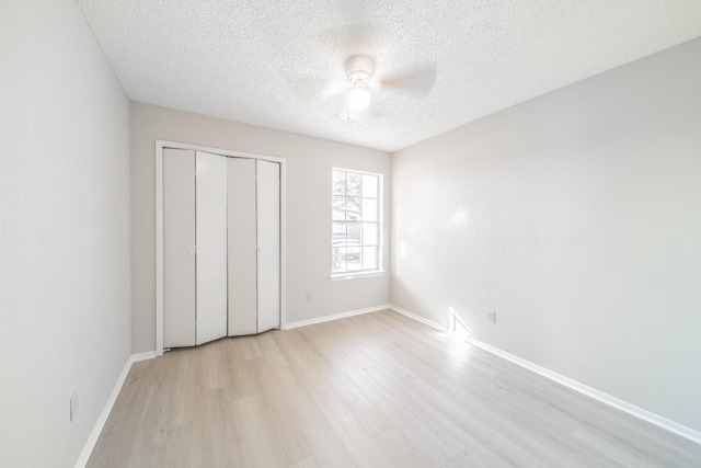 unfurnished bedroom featuring ceiling fan, light hardwood / wood-style floors, a closet, and a textured ceiling