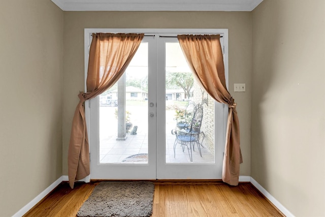 doorway with french doors, crown molding, and light hardwood / wood-style flooring