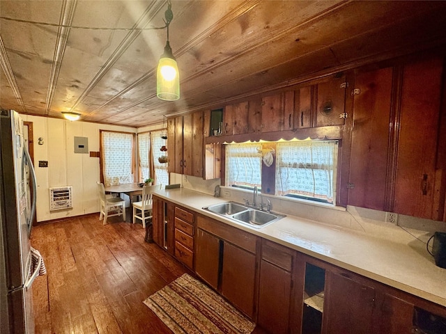 kitchen with dark hardwood / wood-style floors, pendant lighting, heating unit, sink, and stainless steel fridge