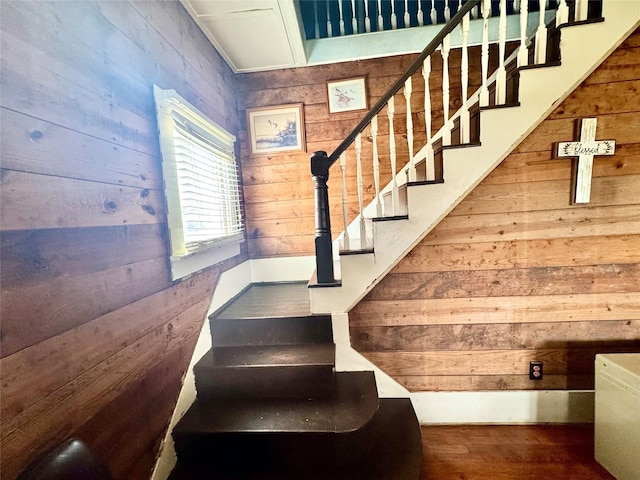 staircase featuring hardwood / wood-style floors and wooden walls