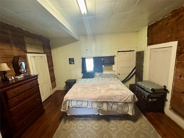 bedroom with dark hardwood / wood-style floors and wood walls