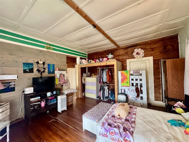 bedroom with wooden walls, radiator heating unit, and dark hardwood / wood-style flooring