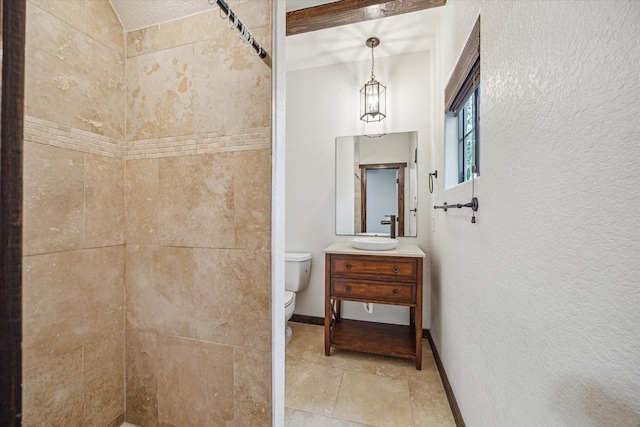 bathroom with vanity, tiled shower, and toilet