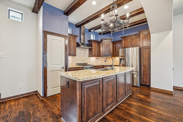 kitchen featuring sink, a center island with sink, appliances with stainless steel finishes, light stone countertops, and wall chimney range hood