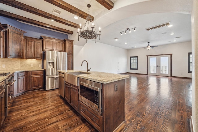 kitchen featuring dark wood-type flooring, appliances with stainless steel finishes, sink, and a center island with sink