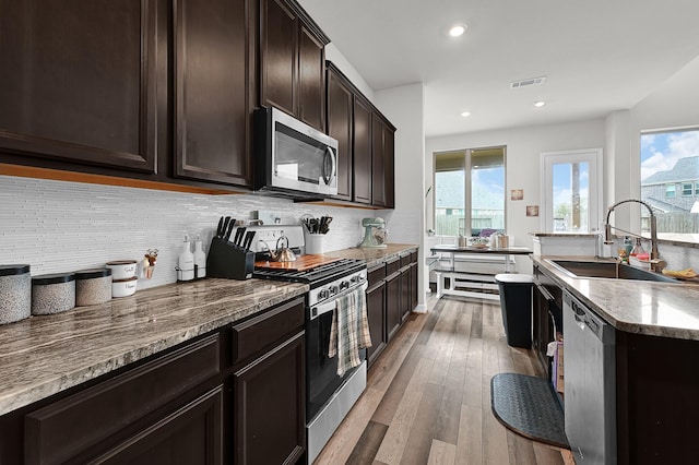 kitchen with hardwood / wood-style floors, sink, backsplash, dark brown cabinetry, and stainless steel appliances