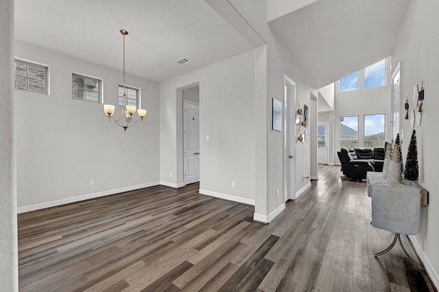 interior space with a high ceiling, dark wood-type flooring, and a notable chandelier