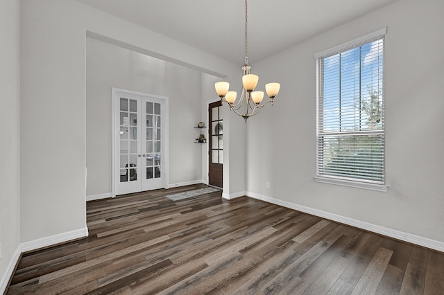 unfurnished dining area featuring dark hardwood / wood-style floors, a chandelier, and french doors