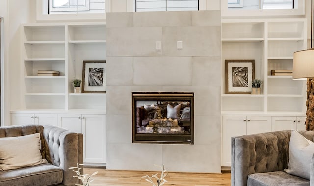 sitting room featuring built in shelves, a fireplace, and light hardwood / wood-style floors