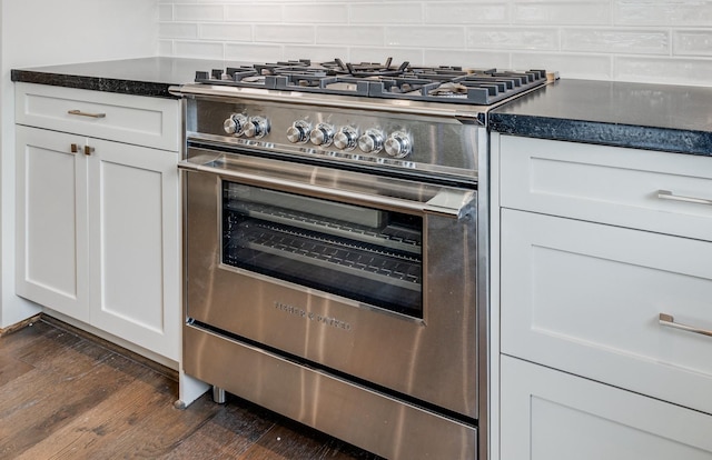 kitchen with high end stainless steel range oven, white cabinetry, dark wood-type flooring, and backsplash