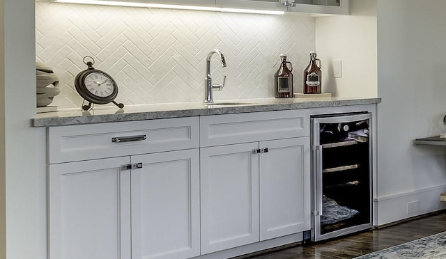 bar featuring backsplash, beverage cooler, sink, and white cabinets