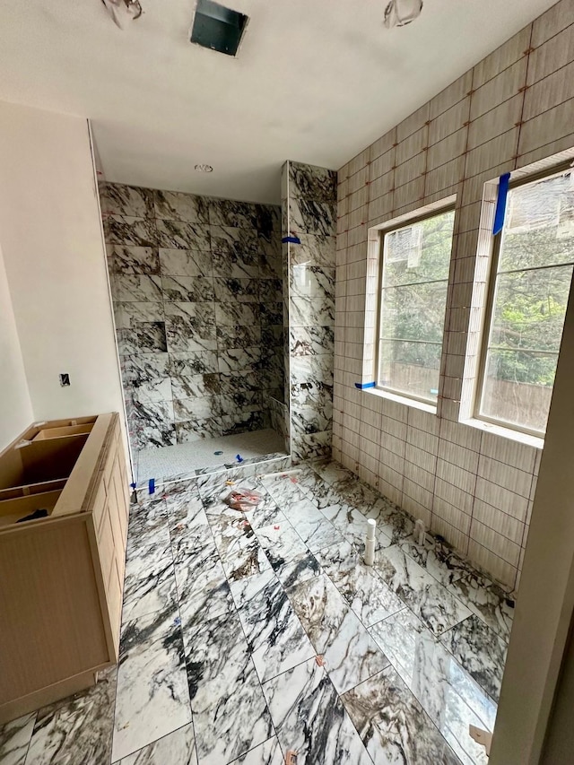 2434 Quenby St, Houston, TX 77005 - bathroom featuring tiled shower, tile walls, and marble look tile flooring