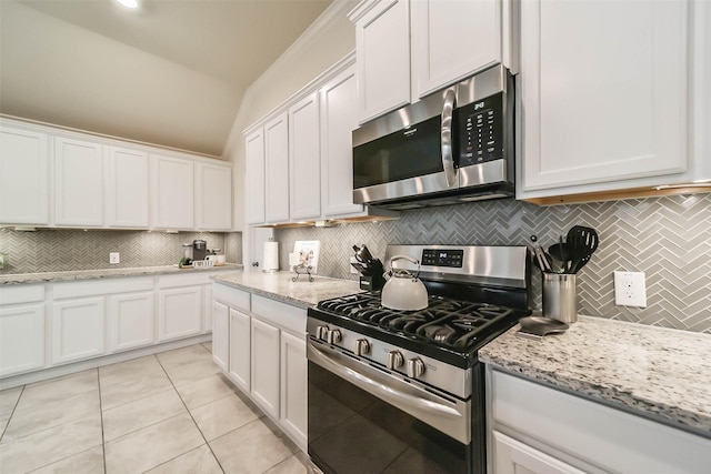 kitchen featuring stainless steel appliances, white cabinetry, light stone countertops, and tasteful backsplash