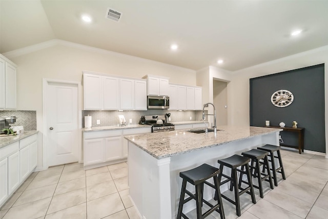 kitchen featuring sink, white cabinetry, light stone counters, an island with sink, and stainless steel appliances