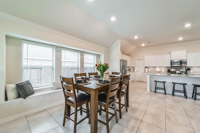 tiled dining room featuring crown molding, lofted ceiling, and sink