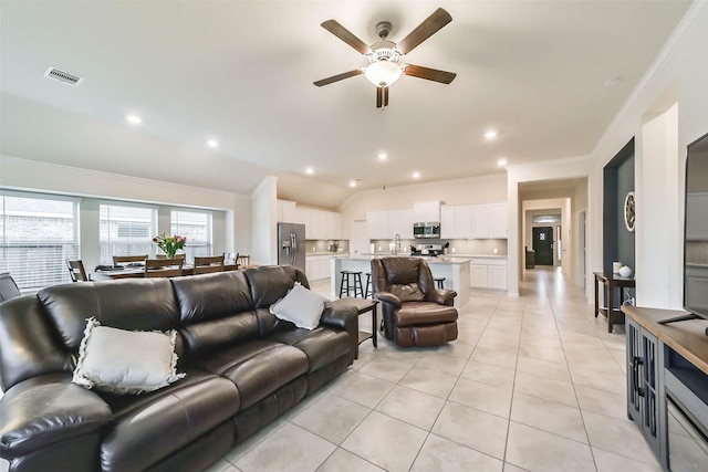 living room with light tile patterned flooring, lofted ceiling, sink, and ceiling fan