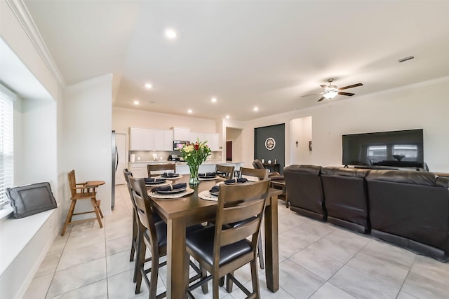 tiled dining space featuring crown molding and ceiling fan