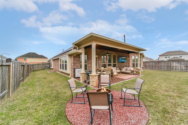 back of property with ceiling fan, a patio area, a lawn, and an outdoor living space with a fire pit