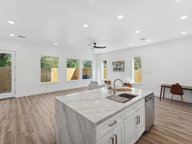 kitchen with white cabinetry, a wealth of natural light, stainless steel dishwasher, and an island with sink