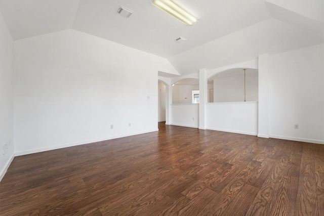 spare room featuring dark wood-type flooring and lofted ceiling