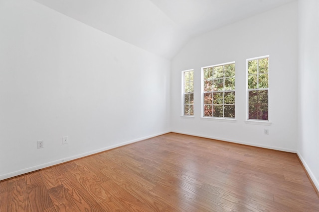 spare room with vaulted ceiling and light hardwood / wood-style flooring