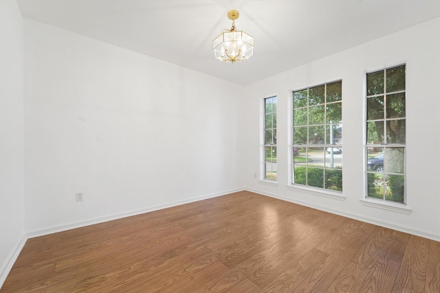 spare room with hardwood / wood-style flooring and a notable chandelier