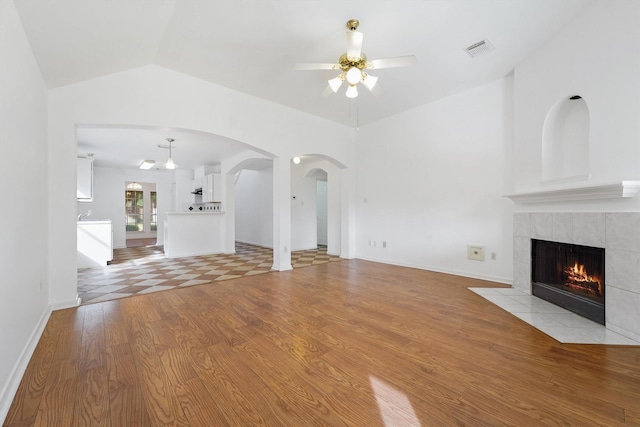 unfurnished living room featuring ceiling fan, lofted ceiling, a fireplace, and light hardwood / wood-style flooring