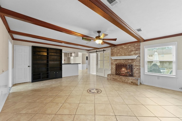 unfurnished living room featuring beam ceiling, ornamental molding, and a barn door