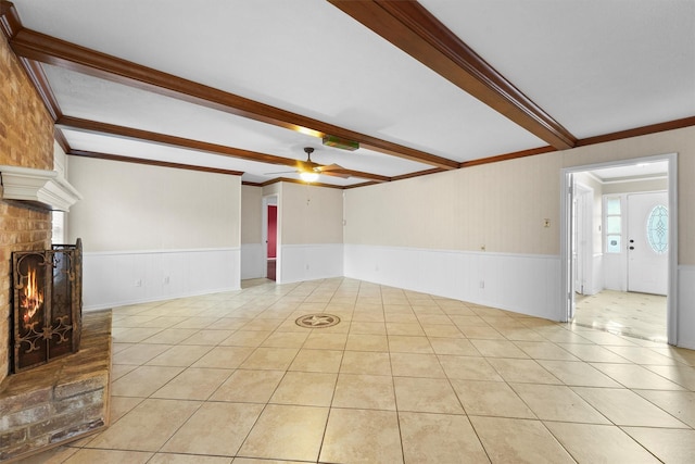 unfurnished living room featuring light tile patterned flooring, a brick fireplace, ornamental molding, ceiling fan, and beam ceiling