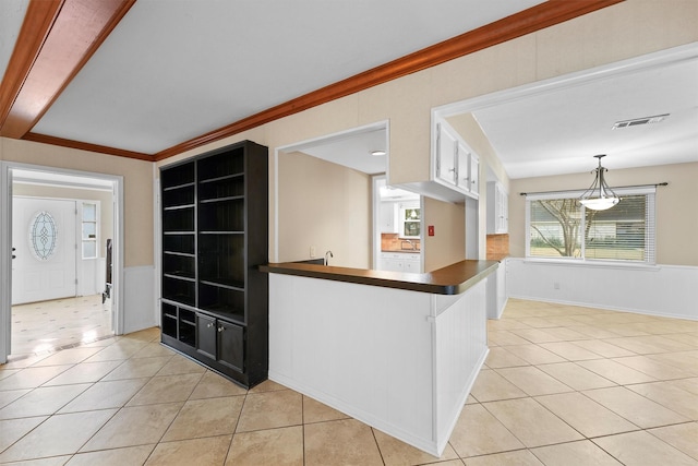 kitchen featuring pendant lighting, white cabinetry, ornamental molding, light tile patterned flooring, and kitchen peninsula